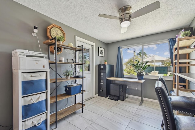 tiled office featuring a ceiling fan, a textured ceiling, and baseboards