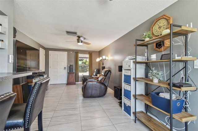 living area featuring a ceiling fan, visible vents, a textured ceiling, and tile patterned floors