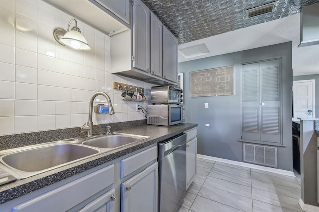 kitchen with a sink, visible vents, appliances with stainless steel finishes, decorative backsplash, and dark countertops