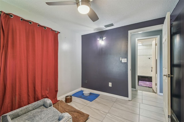 interior space with light tile patterned floors, baseboards, visible vents, ceiling fan, and a textured ceiling