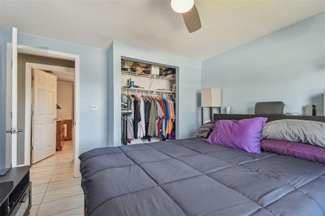 bedroom with light tile patterned floors, a textured ceiling, a ceiling fan, and a closet