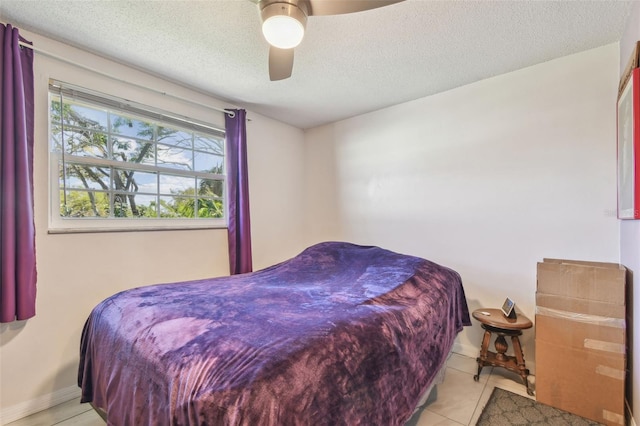 tiled bedroom featuring ceiling fan, a textured ceiling, and baseboards