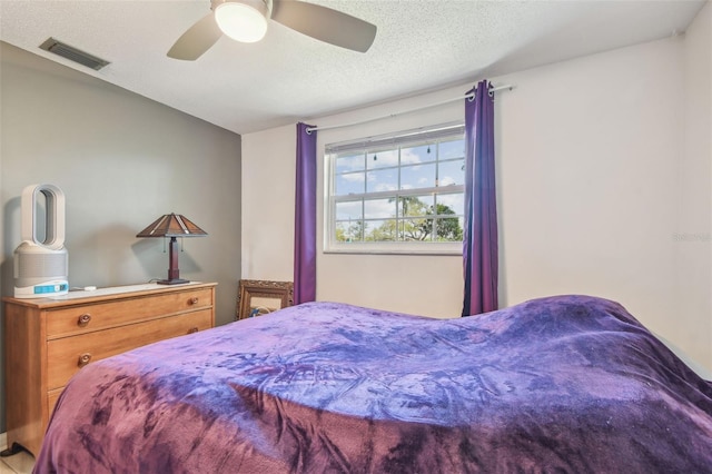 bedroom featuring a textured ceiling, visible vents, and a ceiling fan