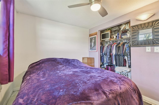 tiled bedroom featuring a ceiling fan, a closet, a textured ceiling, and baseboards