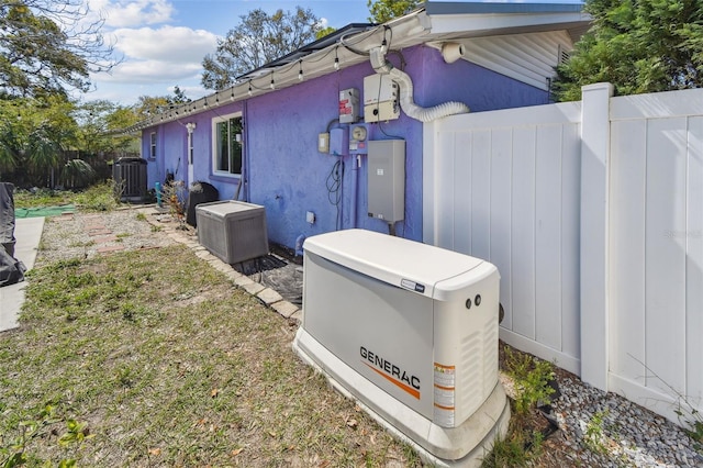 view of side of home with central AC, fence, and stucco siding