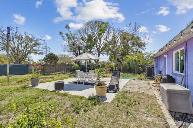 view of yard with a fenced backyard, central AC unit, and a patio