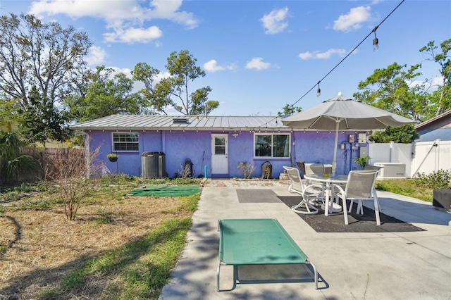 back of property with metal roof, fence, stucco siding, a standing seam roof, and a patio area