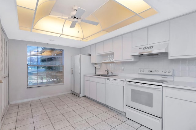 kitchen featuring under cabinet range hood, white appliances, a sink, light countertops, and tasteful backsplash