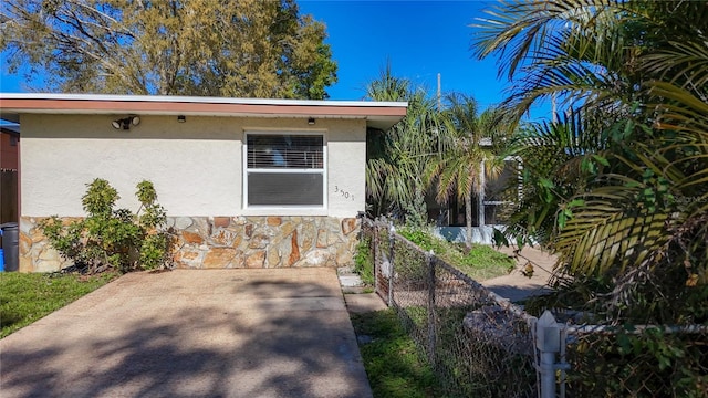 view of home's exterior featuring stone siding, fence, and stucco siding