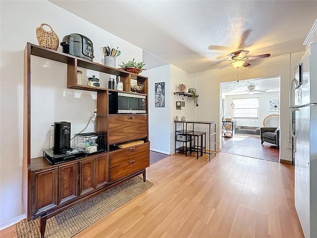 interior space featuring light wood-type flooring, ceiling fan, and baseboards