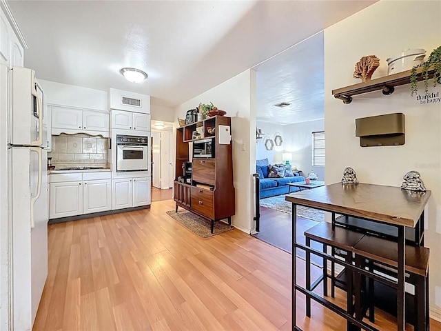 kitchen featuring light wood-type flooring, white appliances, white cabinets, and visible vents