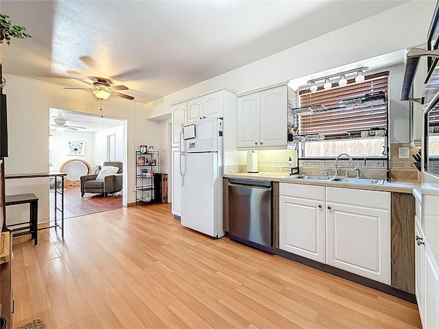 kitchen featuring light wood-style flooring, freestanding refrigerator, white cabinets, a sink, and dishwasher