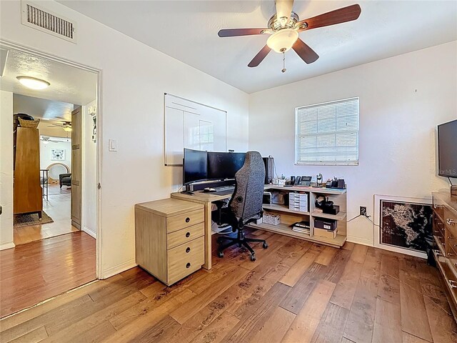 office space featuring light wood-type flooring, ceiling fan, visible vents, and baseboards