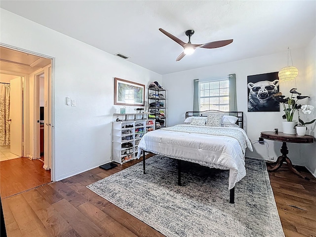 bedroom featuring baseboards, wood finished floors, visible vents, and a ceiling fan