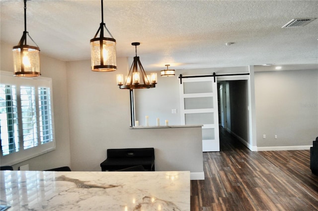 kitchen with visible vents, dark wood finished floors, a textured ceiling, and a barn door