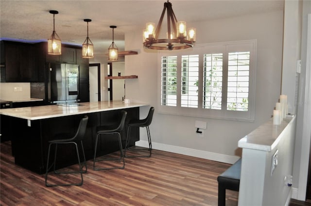 kitchen with baseboards, dark wood finished floors, a kitchen breakfast bar, light countertops, and smart refrigerator