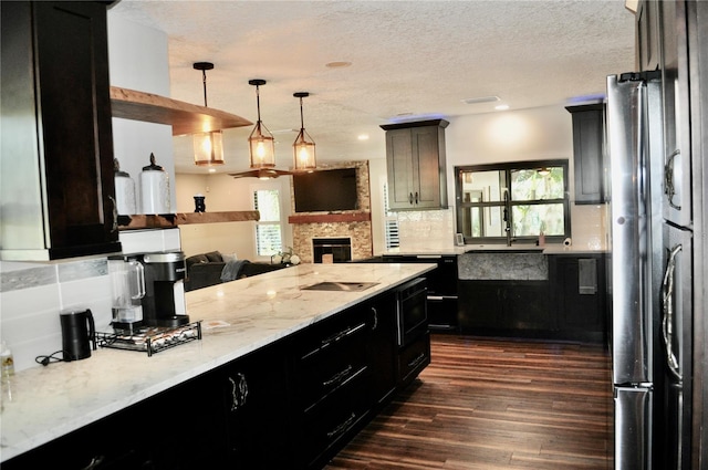 kitchen with a textured ceiling, light stone counters, dark wood-style flooring, backsplash, and freestanding refrigerator