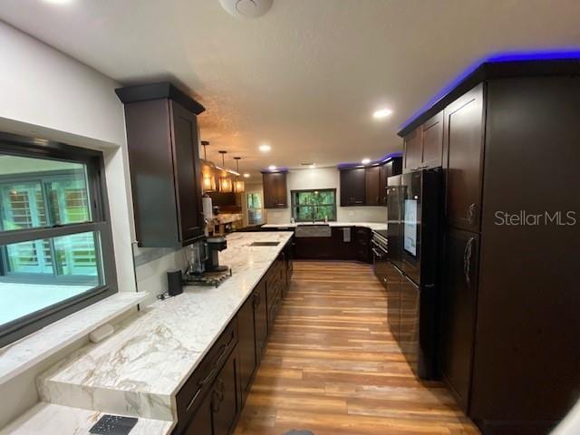 kitchen featuring light wood finished floors, decorative light fixtures, freestanding refrigerator, dark brown cabinets, and recessed lighting