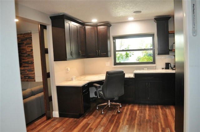 office with a textured ceiling, built in desk, dark wood-style flooring, and recessed lighting