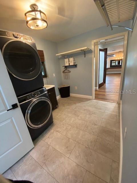 washroom featuring stacked washer and dryer, laundry area, and baseboards