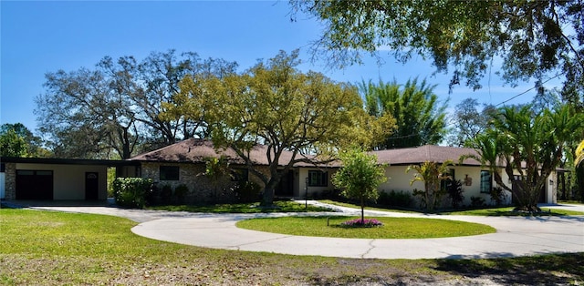 ranch-style home featuring stone siding, a front lawn, and curved driveway