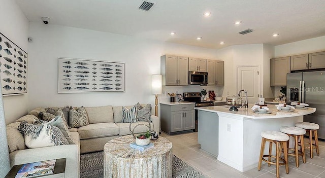 kitchen with a kitchen island with sink, gray cabinetry, visible vents, light countertops, and appliances with stainless steel finishes