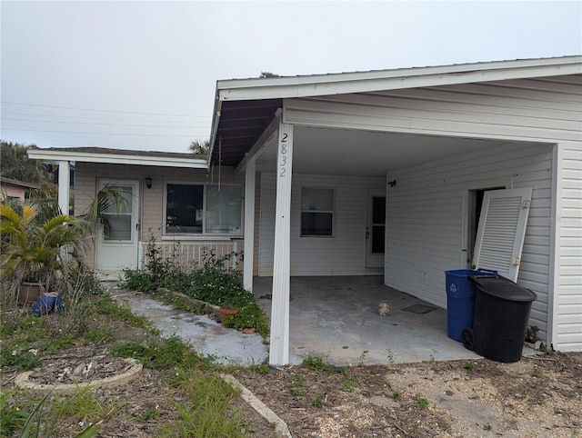 doorway to property featuring dirt driveway and an attached carport