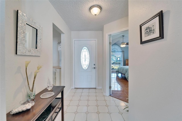 foyer featuring a textured ceiling and baseboards