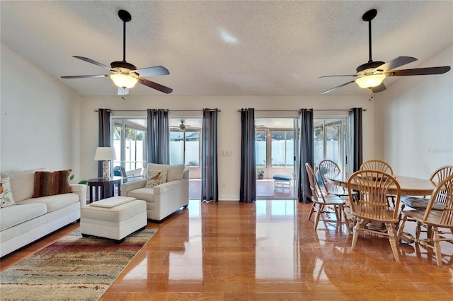 living area featuring vaulted ceiling, ceiling fan, and a textured ceiling