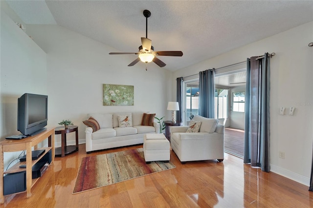 living area with lofted ceiling, baseboards, light wood-style flooring, and a ceiling fan