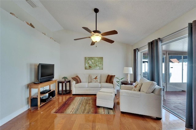 living area with visible vents, a ceiling fan, vaulted ceiling, wood finished floors, and baseboards