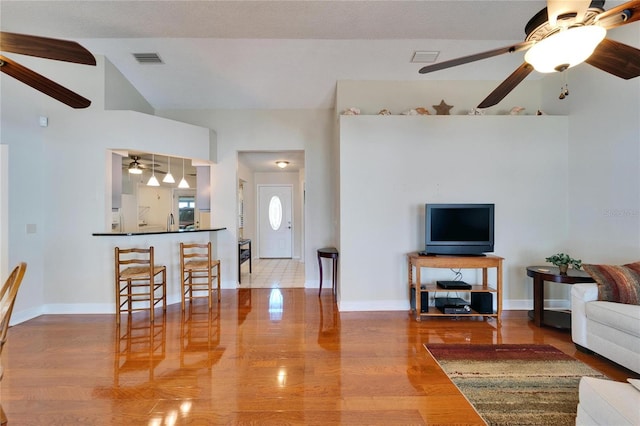 living area with a ceiling fan, baseboards, visible vents, and wood finished floors