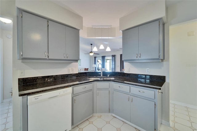 kitchen featuring dark stone countertops, gray cabinets, dishwasher, and a sink