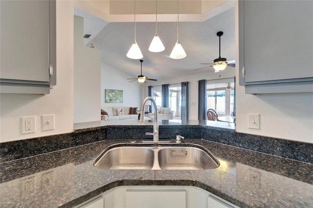 kitchen featuring lofted ceiling, open floor plan, a sink, and gray cabinetry