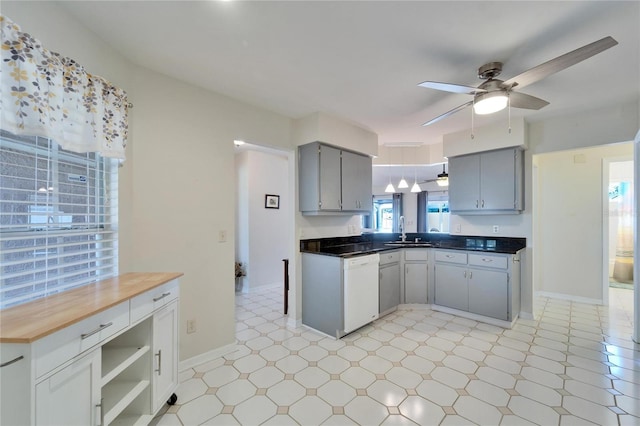 kitchen featuring a ceiling fan, white dishwasher, gray cabinetry, light floors, and a sink