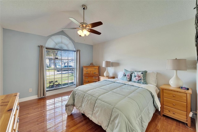 bedroom with a ceiling fan, lofted ceiling, baseboards, and wood finished floors