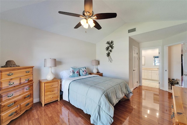 bedroom with lofted ceiling, visible vents, light wood-style flooring, ceiling fan, and ensuite bath