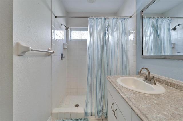 bathroom with a textured wall, a shower stall, and vanity