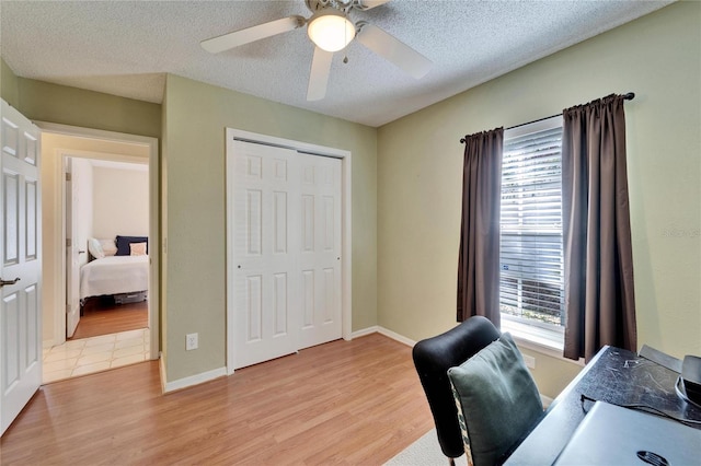 office space with light wood-style floors, a textured ceiling, and baseboards