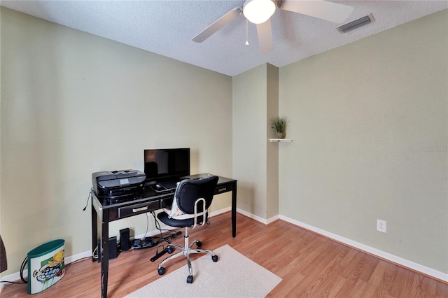 office area featuring a ceiling fan, wood finished floors, visible vents, and baseboards