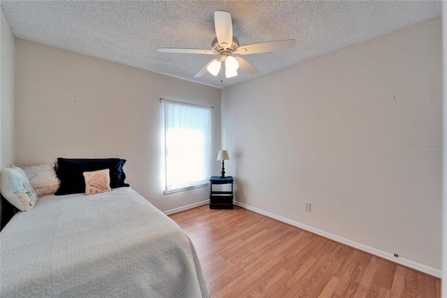 bedroom featuring a textured ceiling, ceiling fan, light wood-type flooring, and baseboards