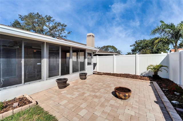 view of patio / terrace with a sunroom, a fenced backyard, and a fire pit