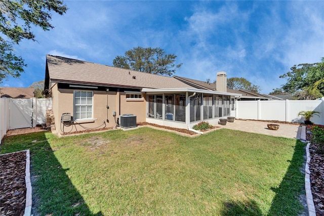 rear view of property with a patio, a chimney, a lawn, a sunroom, and a fenced backyard