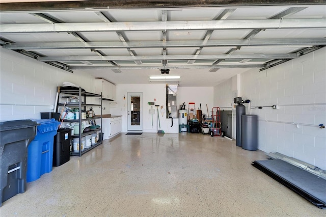 garage with a garage door opener, concrete block wall, and electric water heater