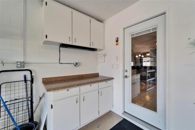 kitchen featuring light speckled floor, dark countertops, white cabinetry, and a textured ceiling