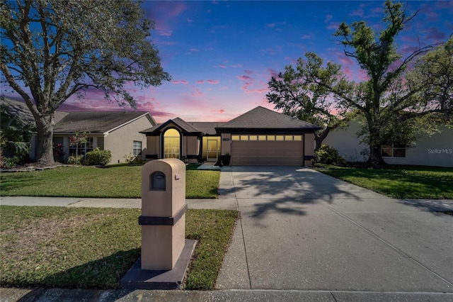 view of front facade with a garage, driveway, a front yard, and stucco siding