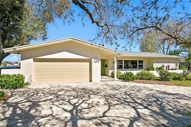 single story home with a garage, decorative driveway, and brick siding