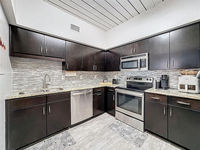 kitchen featuring appliances with stainless steel finishes, a sink, dark brown cabinetry, and tasteful backsplash