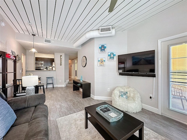 living area with wood ceiling, light wood-type flooring, visible vents, and baseboards