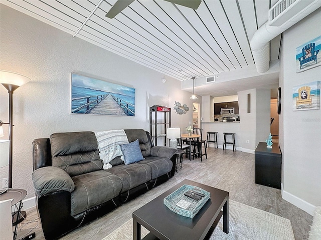 living area featuring wood finished floors, visible vents, and baseboards